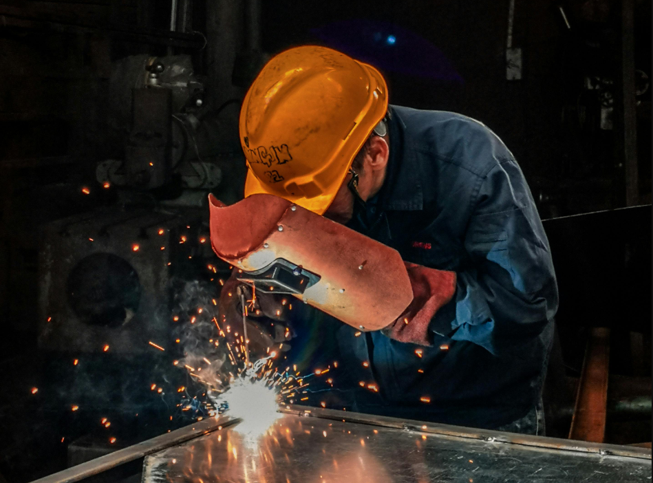 a man wearing a hard hat and welding metal